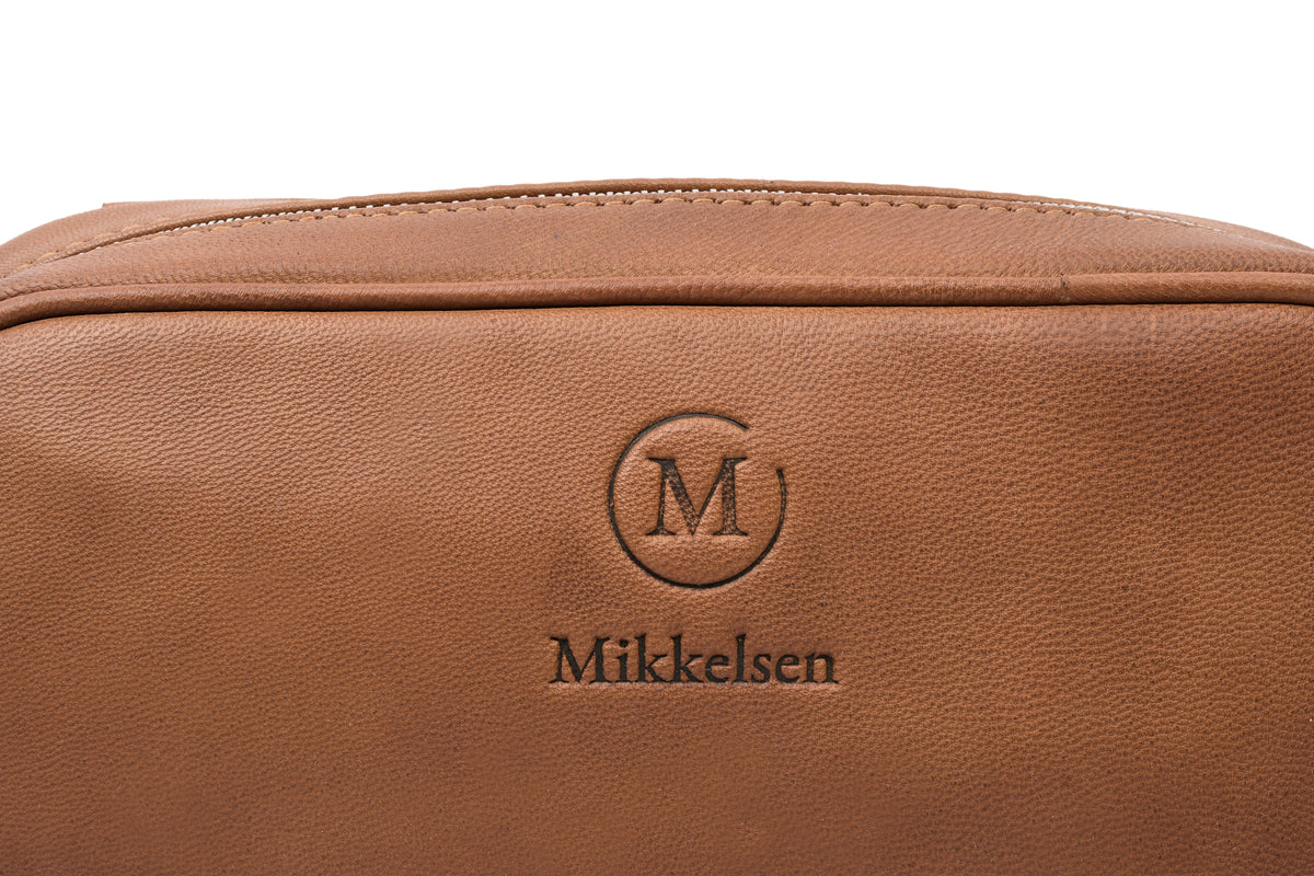 Close-up Cognac leather toiletry bag, Scandinavian travel accessory.