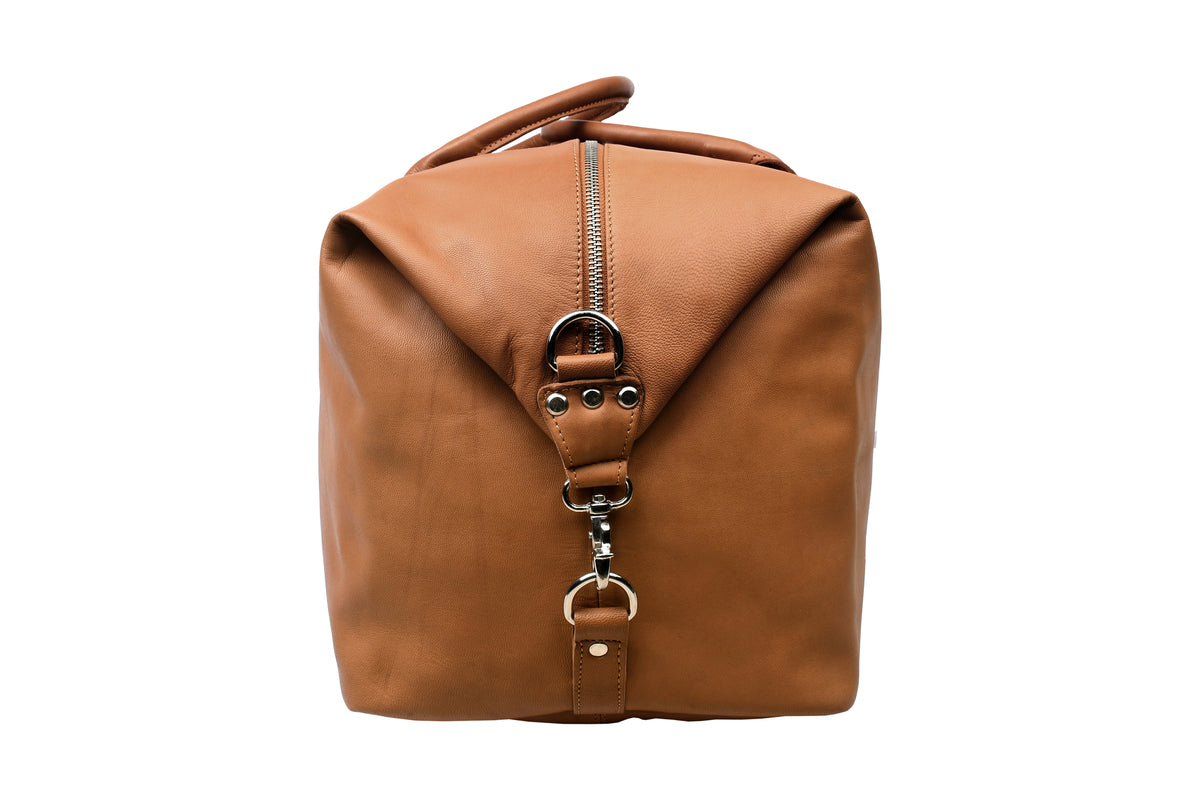 Side view of cognac full-grain leather travel bag with carabiner end closure.