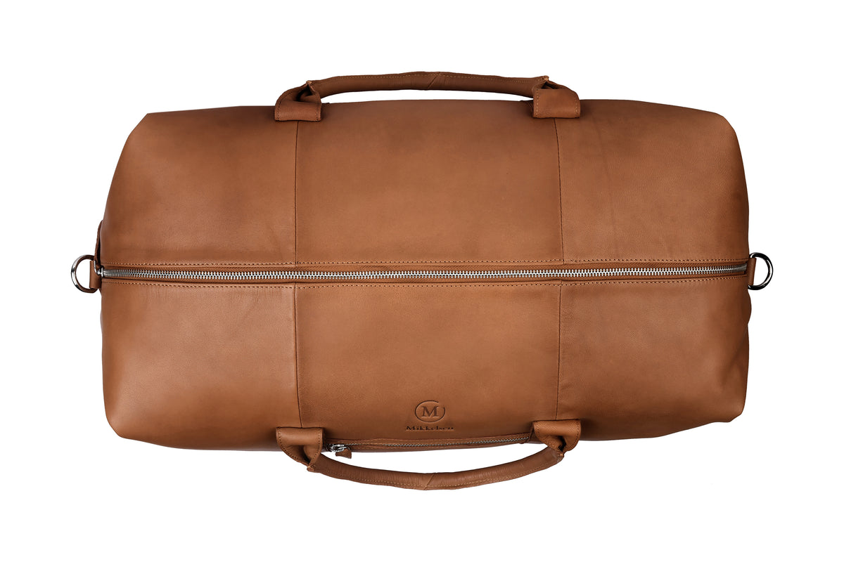 Cognac leather travel bag styled in use, Scandinavian travel accessory.