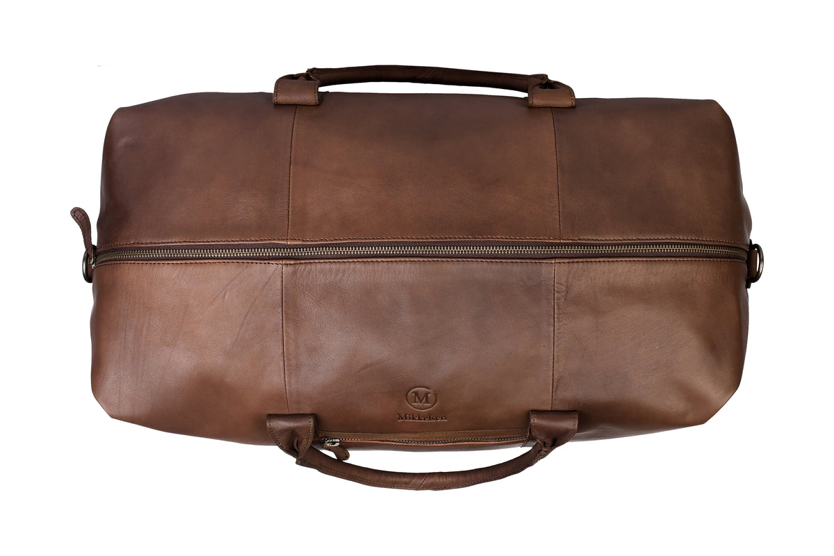 Dark brown leather travel bag styled in use, Scandinavian travel accessory.